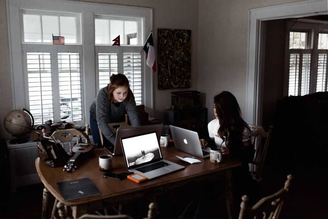 Two female web developers working in a brown table.
