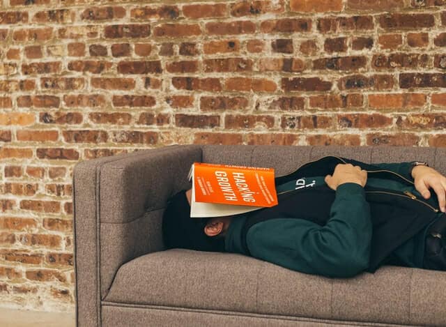 A growth hacker fell asleep on a couch with a book titled "Growth Hacking" on his face.